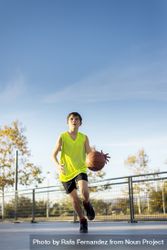 Boy in yellow shirt plays basketball on city playground 5lLXo5