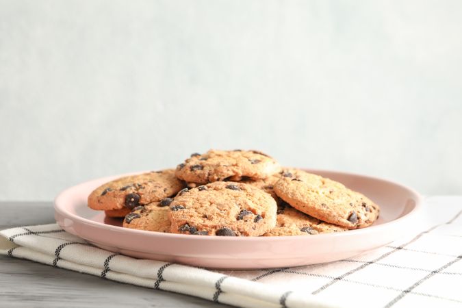 Plate with chocolate chip cookies and space for text on wooden table