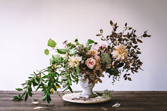 Composition of flowers and plants in vintage vase on board