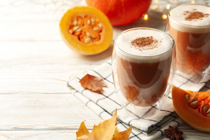 Composition with pumpkin latte on neutral wooden table