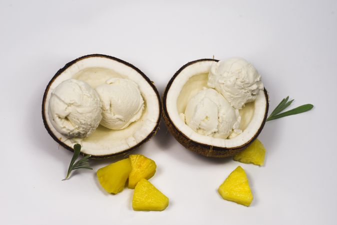 Top view of two coconut shells with delicious ice cream and pineapple fruit chunks