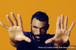 Serious Black man in yellow studio with hands outstretched towards the camera 479zO0