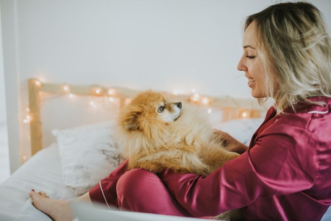 Smiling woman sitting in bed with dog