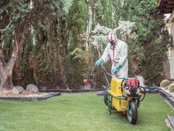 Specialist in uniform for fumigation holding yellow trolley in yard
