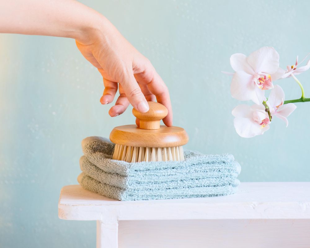 Hand reaching for bathing brush on blue background