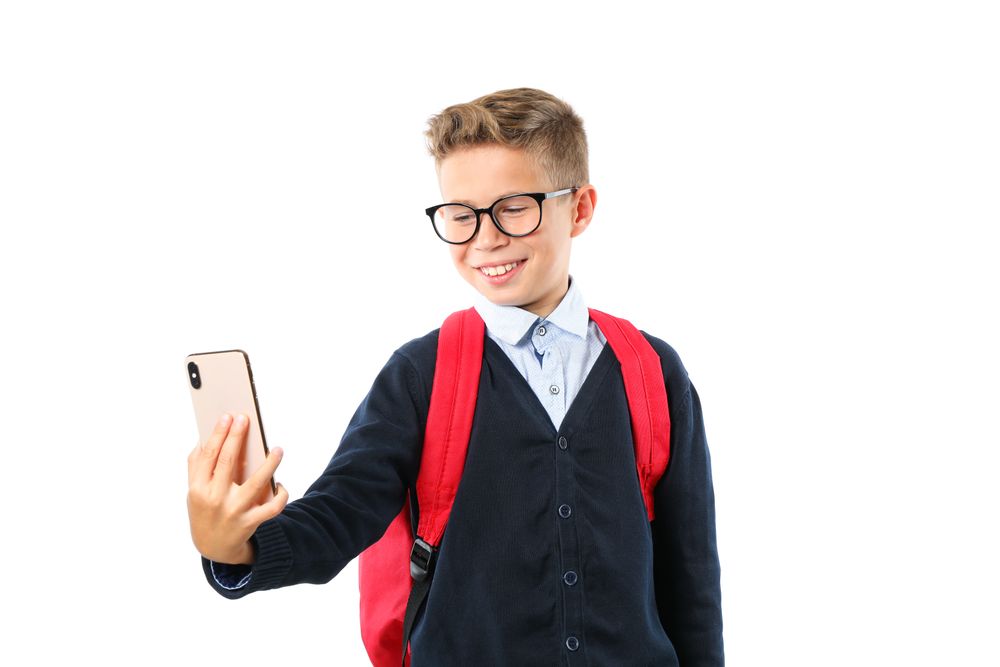 Boy makes selfie on phone isolated on blank background