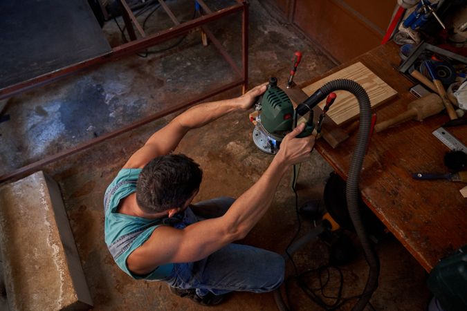 Man grinding wooden plank at joinery