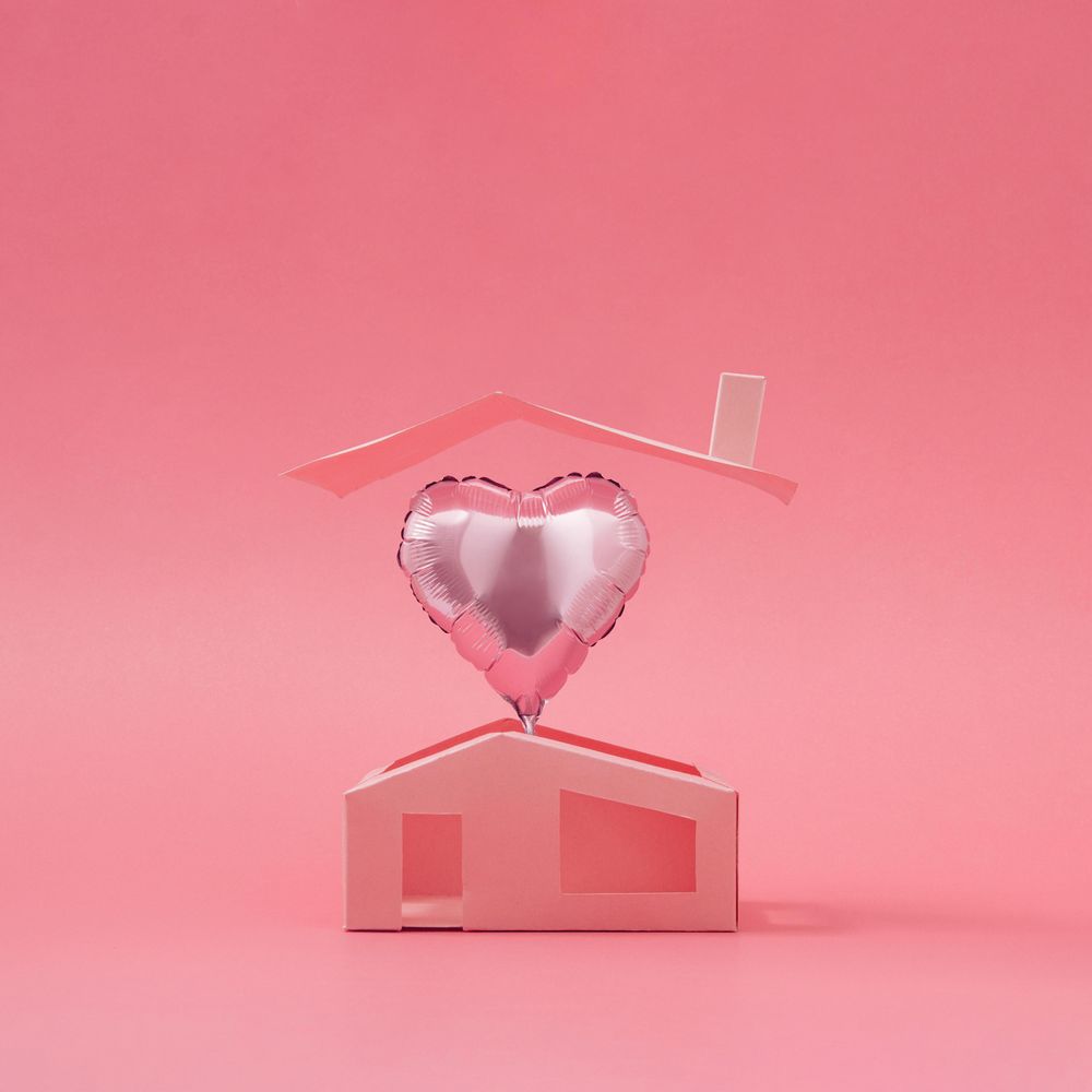 Pink heart balloon above minimalistic house