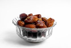 Dates fruits in a bowl glass on isolated plain background