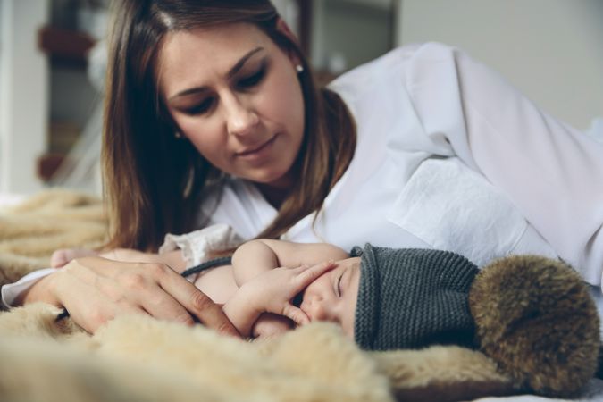 Baby sleeping on a blanket while her mother looks