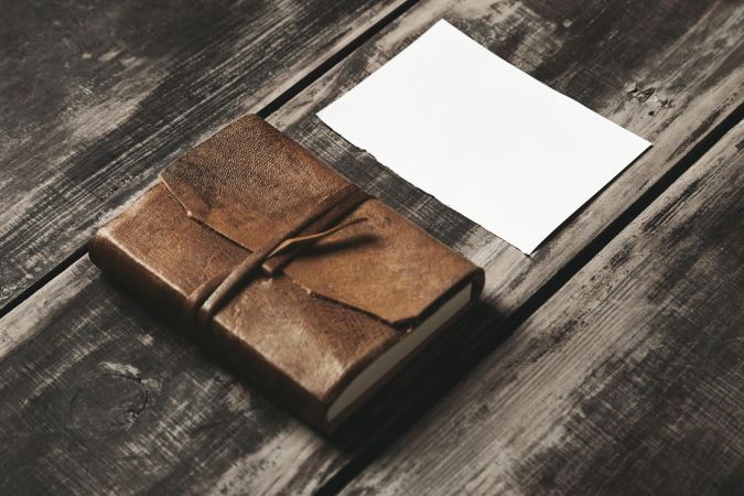 Leather-bound notebook and paper on wooden table