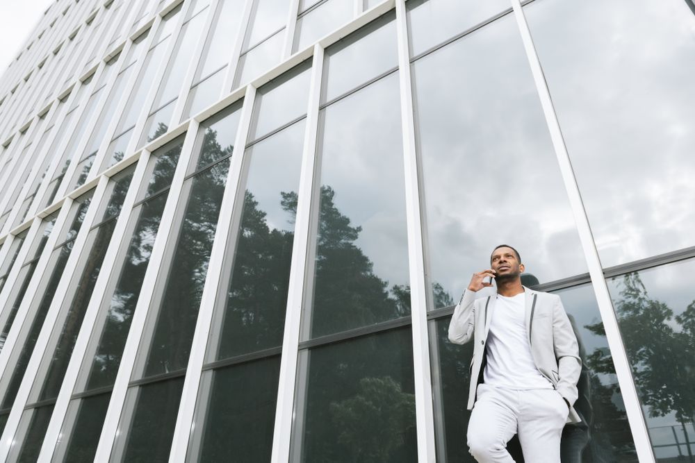 Elegant Black man talking smartphone leaning building