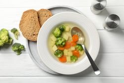 Looking down at vegetable soup on wooden table with break