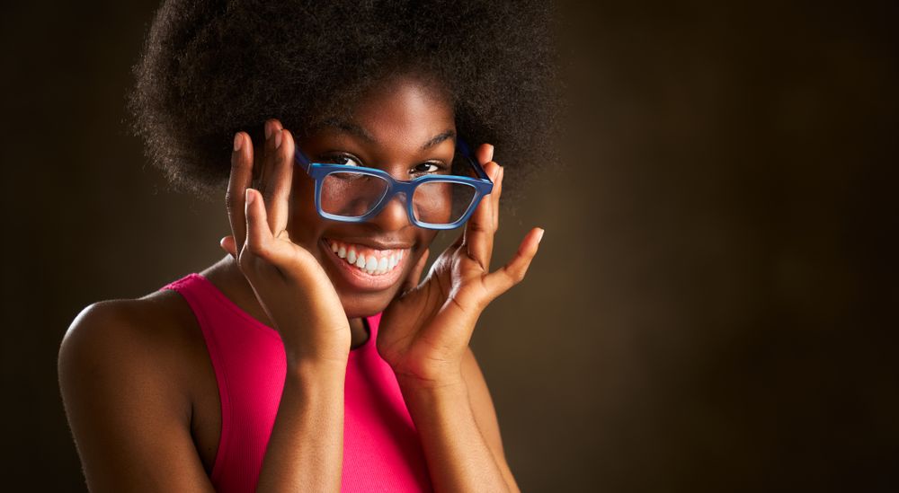 young Black woman with afro hairstyle happy smiling in glasses