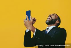 Animated Black businessman in suit laughing at smartphone screen bxkNX4