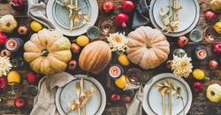 Flat-lay plates, silverware, floral and fruit decoration, candle and pumpkins