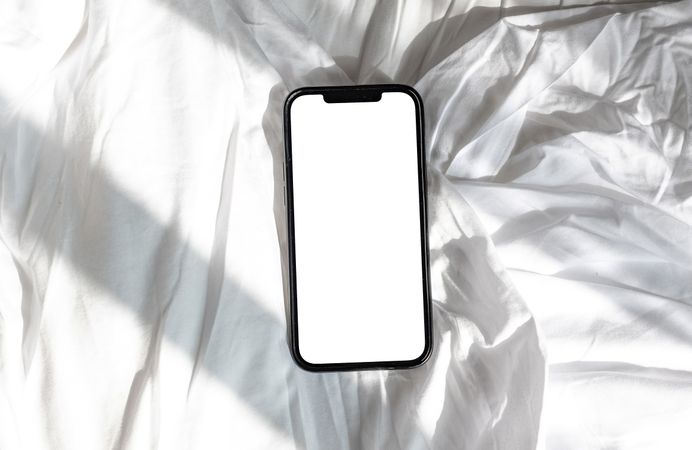 Top view of phone mock up on bed sheet