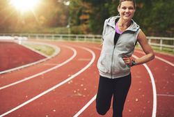 Woman smiling while stretching her quads on athletic track