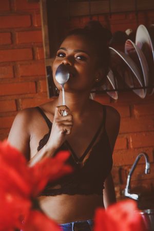 Woman eating with spoon standing in the kitchen