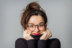 Woman with glasses and red lips taking her neck sweater