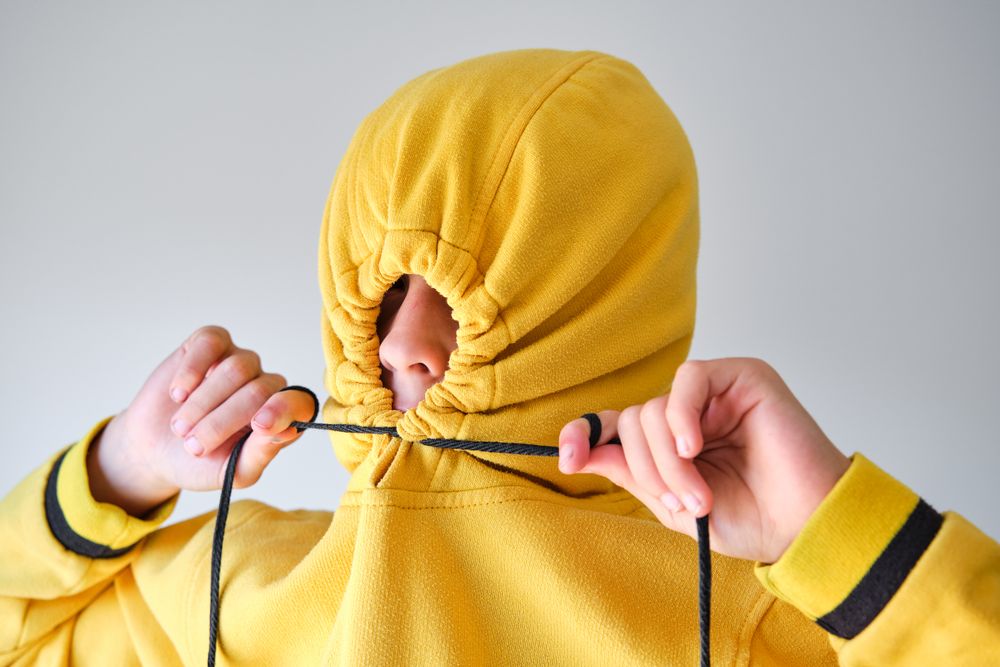 Anonymous child tightening drawstrings on hood
