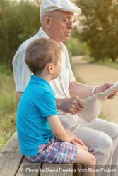 Older man and child reading a newspaper outdoors 4OvlE5