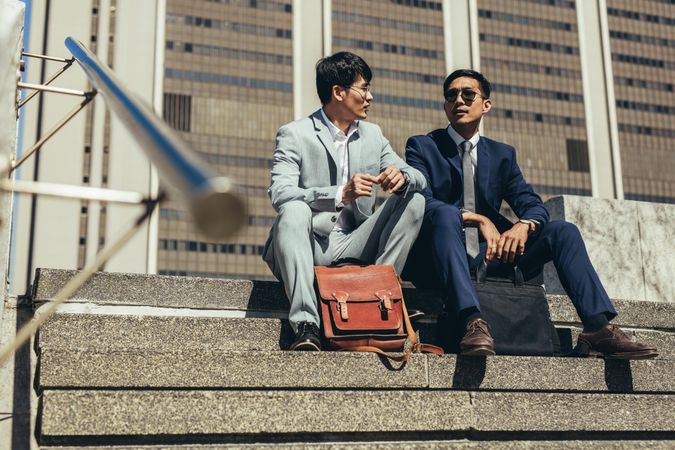 Two business partners sitting on steps outdoors and talking