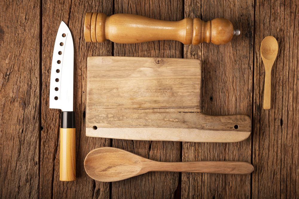 Cutting board with kitchen utensils on rustic background.