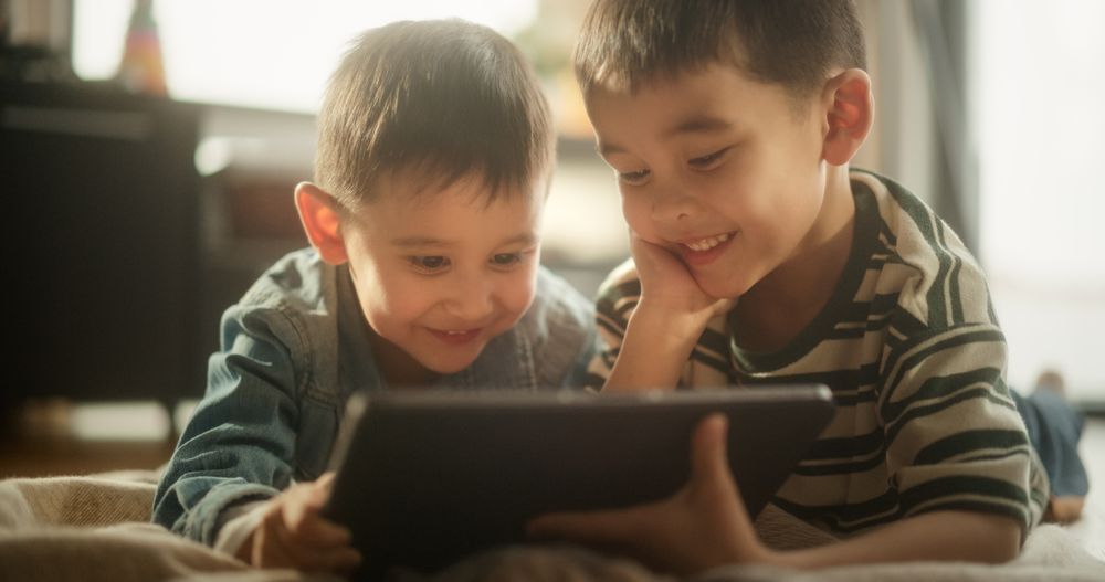Portrait of Two Male Asian Kids Using a Digital Tablet During Weekend in their Room.