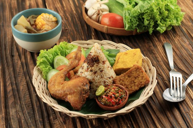 Indonesian chicken dish served with rice, salad and spicy condiment