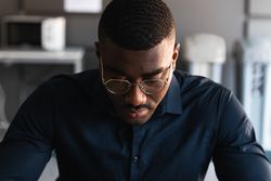 Black guy video chatting on tablet near laptop in workplace