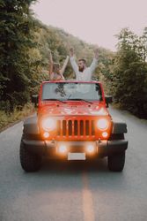 Loving couple sitting on car on road near forest