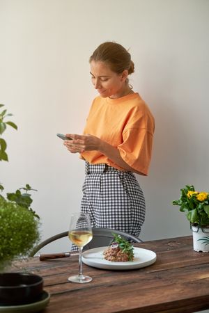 Cheerful female browsing smartphone in kitchen