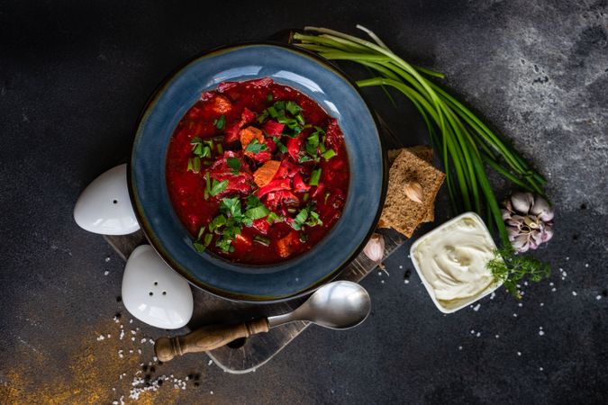 Top view of Ukrainian beetroot soup borscht on counter served with green onions