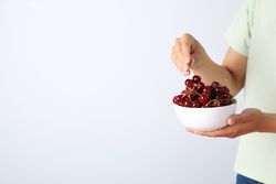 Ripe cherry fruits in a bowl on a light background