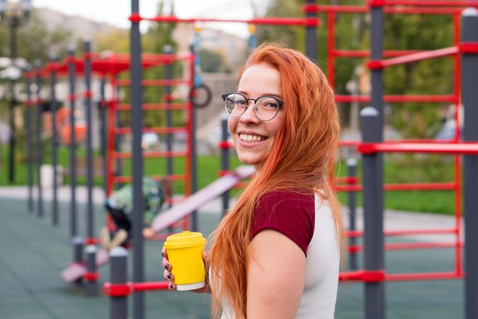 Woman holding yellow cup during break from outdoor workout