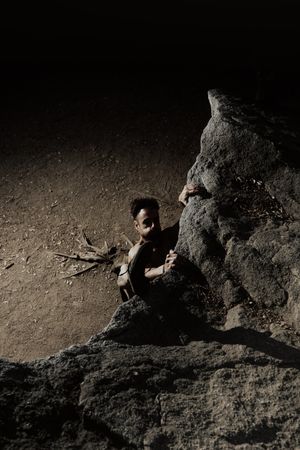 Man practicing rock climbing among large rocks in a forest