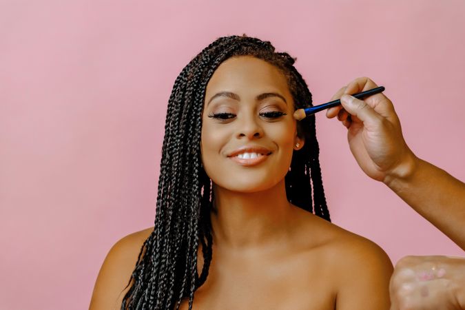 Female smiling while having her make up done in pink studio shoot