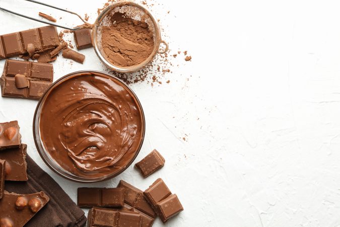 Chocolate, melted chocolate and powder on light background