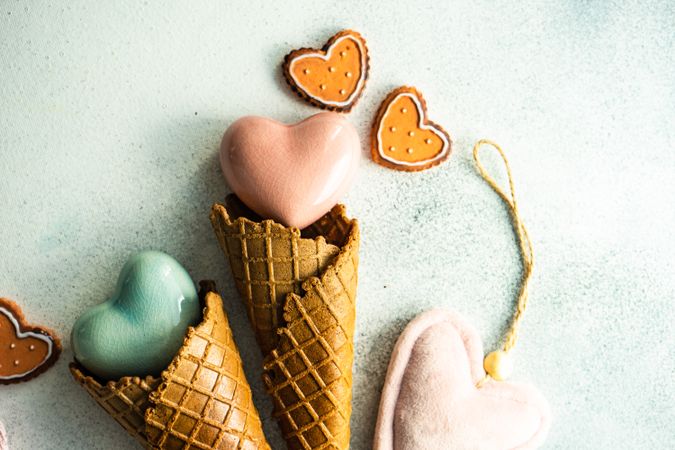 Two ceramic hearts in waffle cones on grey background with various Valentine ornaments