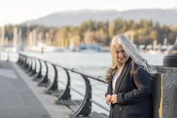 Smiling woman leaning on a lamp post buttoning blazer