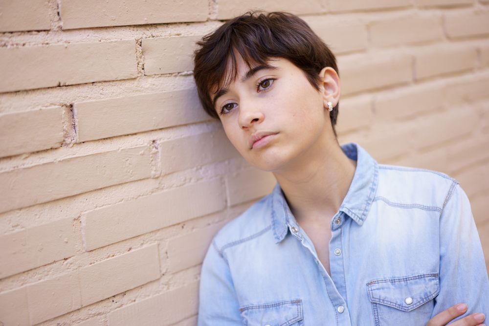 A Young Person Engaged in Contemplation as They Lean Against a Wall, Deep in Thought