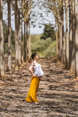 Adult expectant mother practicing yoga in park during sunny day