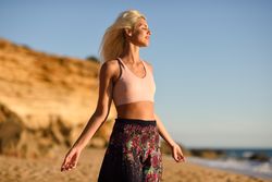 Blonde female facing the ocean on beach at sunset