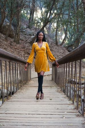 Woman in yellow dress walking on a bridge in the mountains