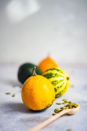 Close up of colorful mini squash on counter with spoons of seeds