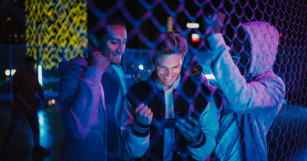 Group of Young Diverse Men Watching a Sports Game on Smartphone Device, Cheering for Their Favorite Team