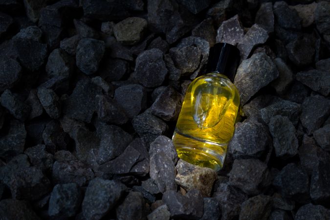 Yellow perfume bottle mock up laying in rocky terrain