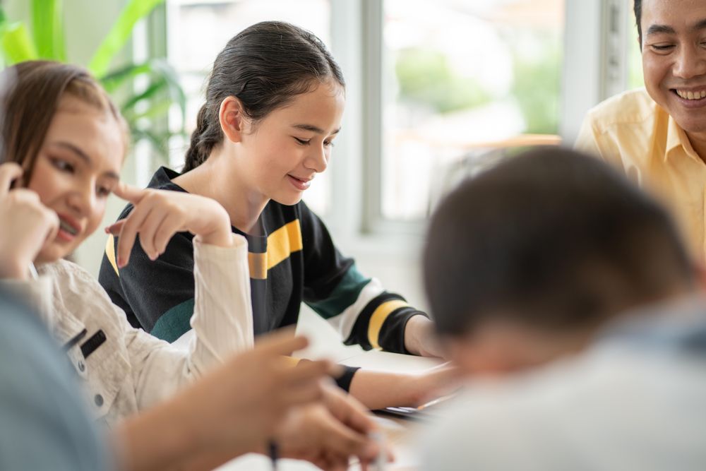 Attentive female student with smiling classmates at school