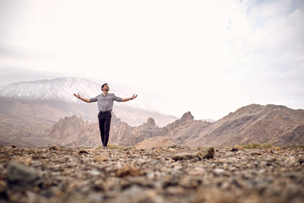 man with outstretched arms in mountains